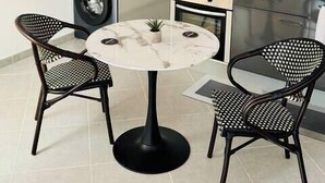 A compact kitchen with a built-in washer and dryer, a small dining table with two chairs, and a coffee maker on the counter. - Stylish City Pad – Walk to All (Bergerac)