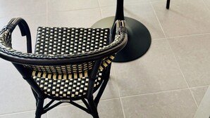 A round marble table with two black wicker chairs, a small potted plant, and a coaster. - Stylish City Pad – Walk to All (Bergerac)