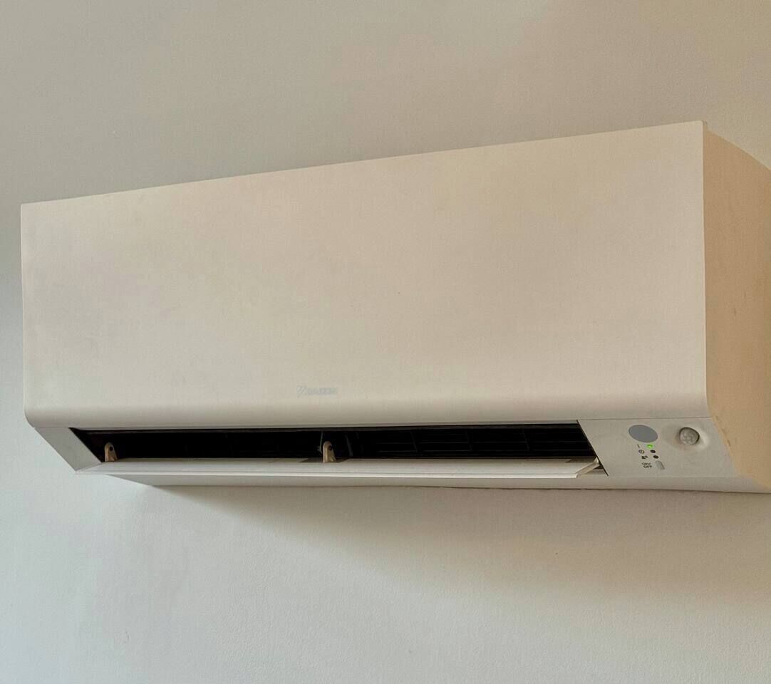 Un appareil de climatisation mural blanc, doté d’un panneau de commande et d’une grille d ’aération.