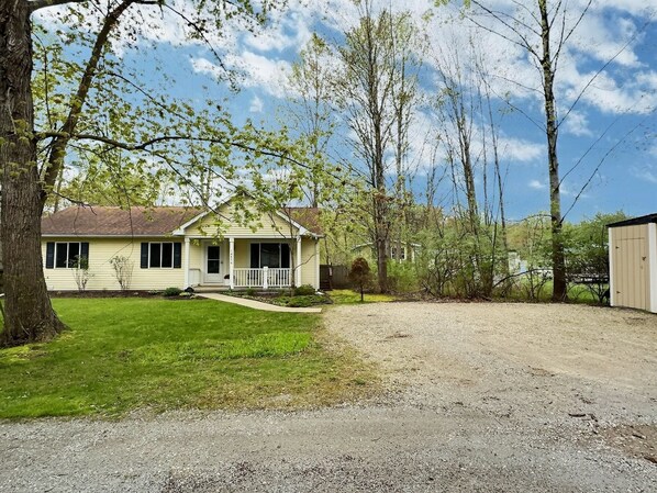 A single-story house with a front porch, a small front yard, and a gravel driveway.