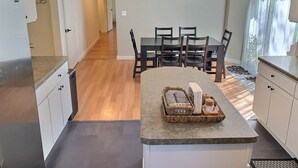 Una cocina moderna con una isla central, suelo de madera y un comedor con mesa y sillas.