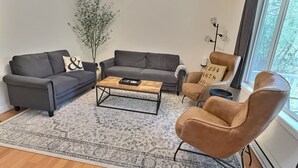 Una sala de estar moderna con un sofá gris, un sillón marrón y una mesa de centro.