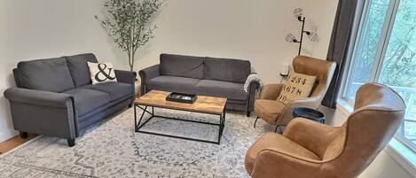A modern living room with a grey sofa, a brown armchair, and a coffee table.
