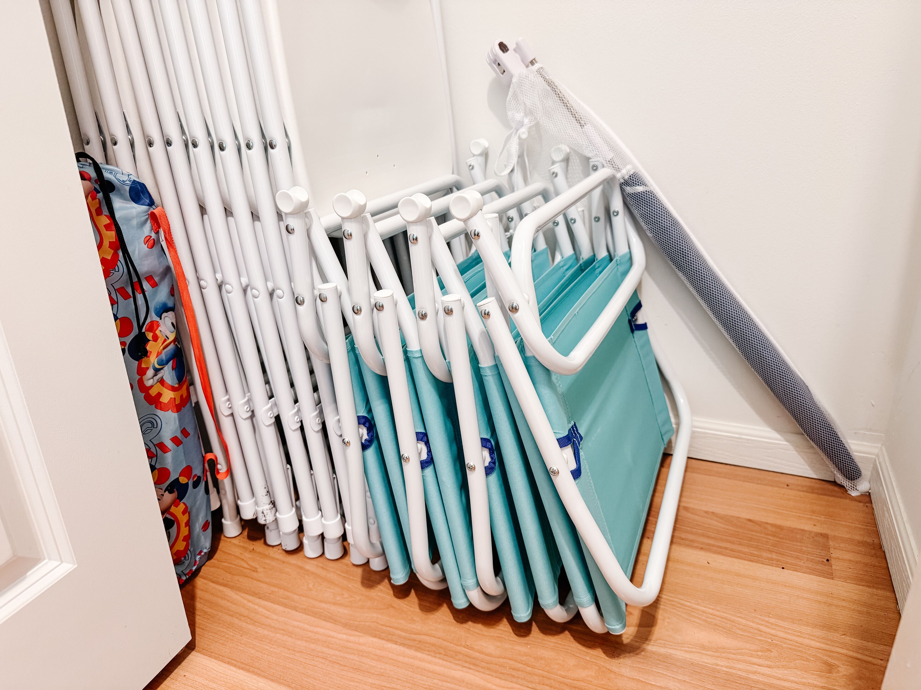 A corner of a room with a white radiator, a blue and white folding chair, and a colorful curtain.