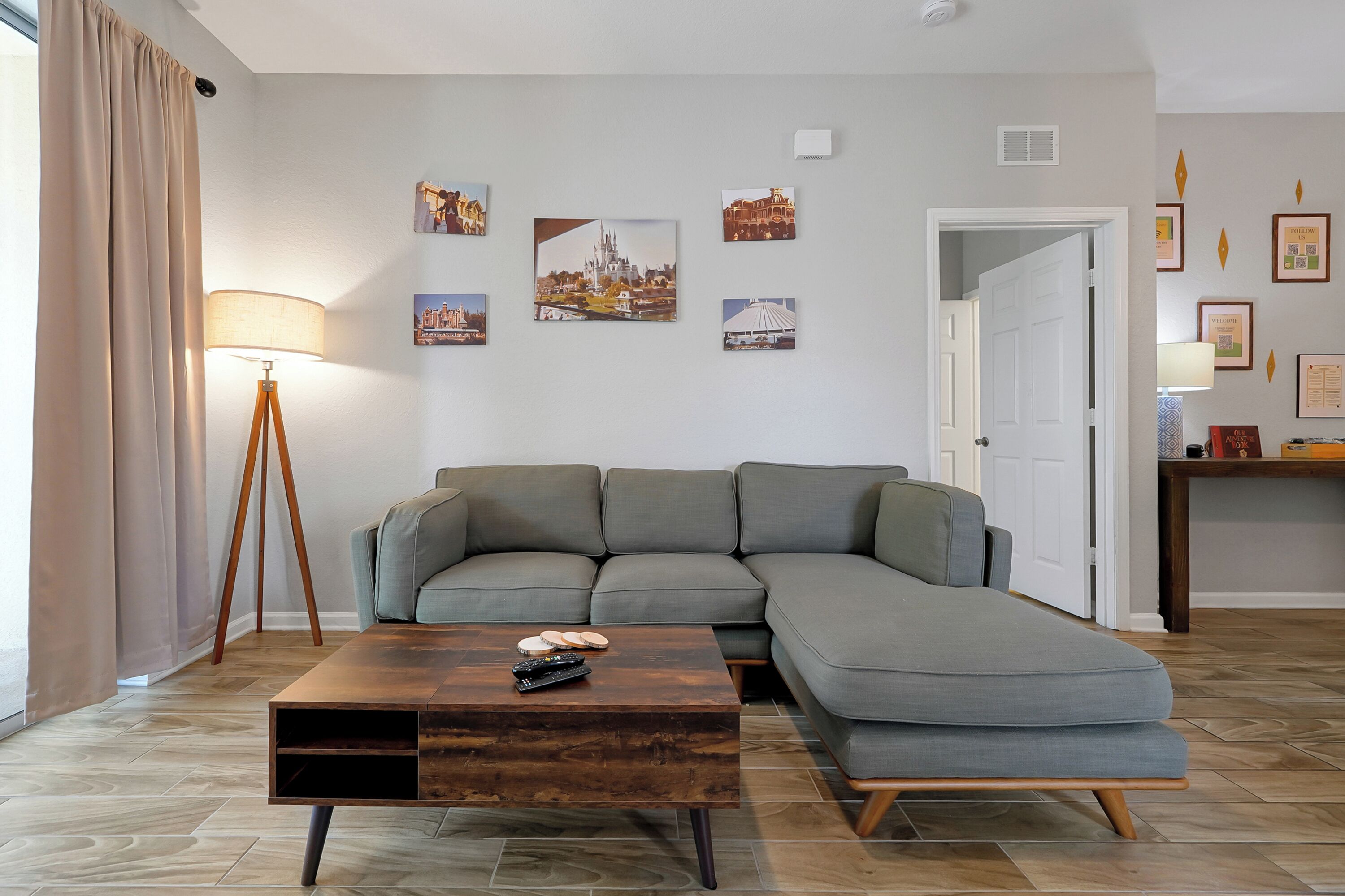 Ein modernes Wohnzimmer mit einem grauen Ecksofa, einem Holztisch und einer Stehlampe.