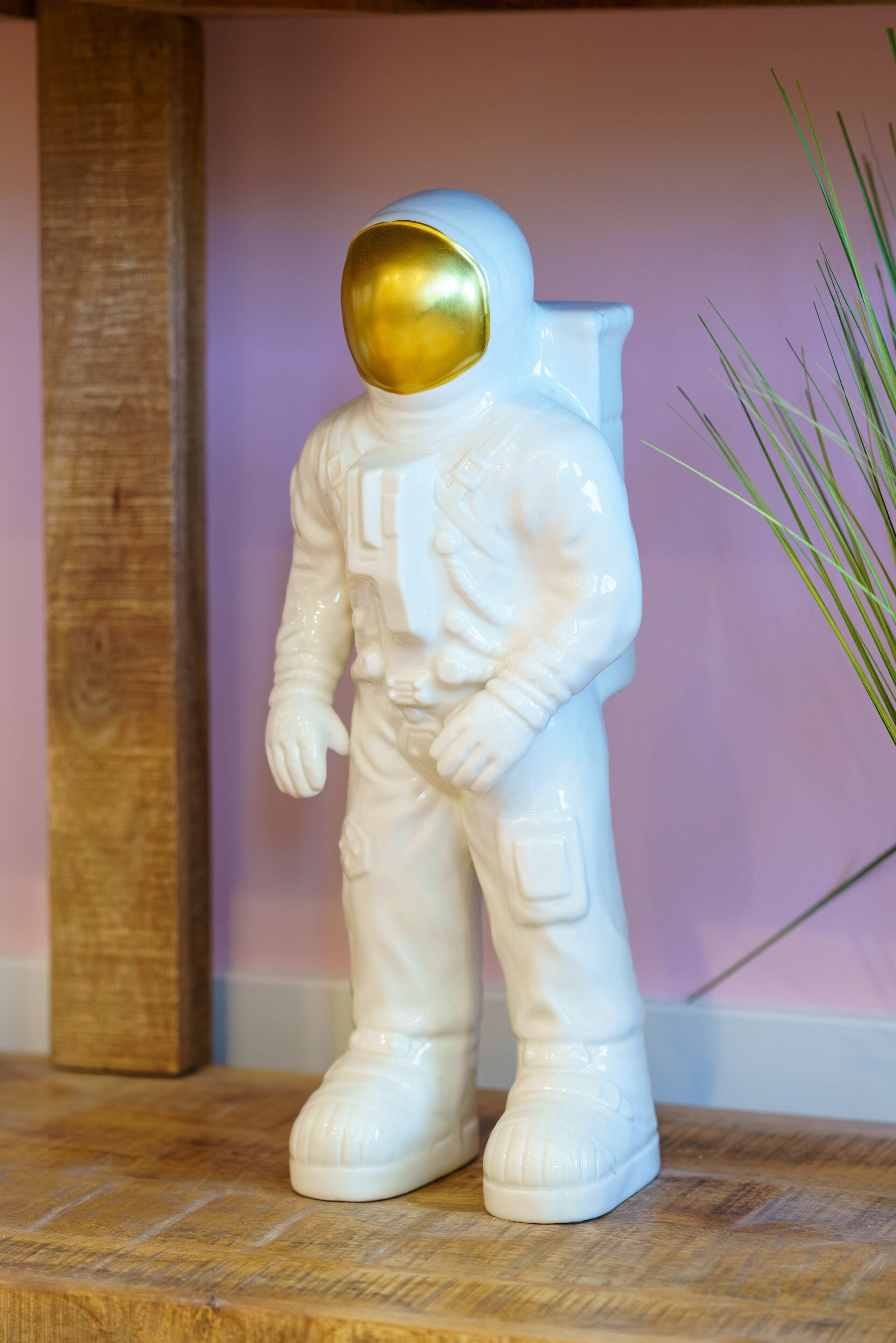 A white astronaut figurine with a gold helmet on a wooden surface.