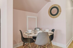 A dining area with a round table, black and grey chairs, and a wall-mounted mirror.