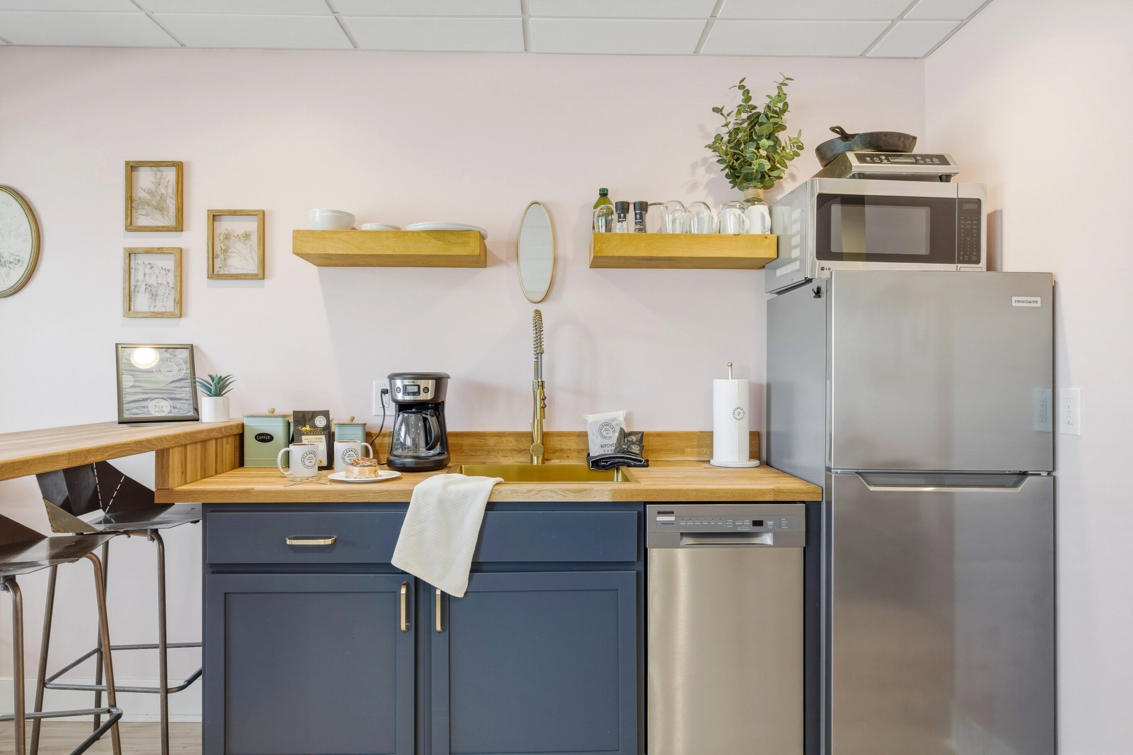 Une cuisine moderne équipée d’un réfrigérateur en acier inoxydable, d’une machine à café, d’un four à micro-ondes et d’un évier.
