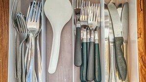 Un tiroir contenant divers ustensiles et accessoires de cuisine, notamment des fourchettes, des cuillères, des couteaux et une pince.