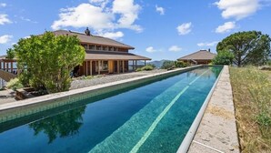 A swimming pool with a clear blue water surface, surrounded by a stone deck and bordered by trees. - Cozy Getaway Ranch House and Estate by Yosemite (Jamestown)