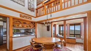 A spacious dining area with a round wooden table and chairs, a decorative rug, and a view through large windows. - Cozy Getaway Ranch House and Estate by Yosemite (Jamestown)