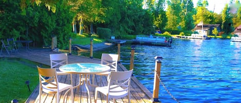 A wooden deck with a table and chairs overlooking a river.