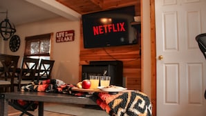 A cozy dining area with a wooden table, chairs, and a TV displaying 'NETFLIX'.