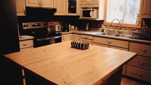 A kitchen with wooden cabinets, a microwave, a sink, and a wooden island.