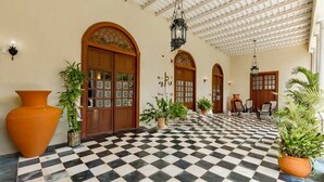 Un hall d’hôtel avec un sol à carreaux, des portes en bois et des plantes en pot.