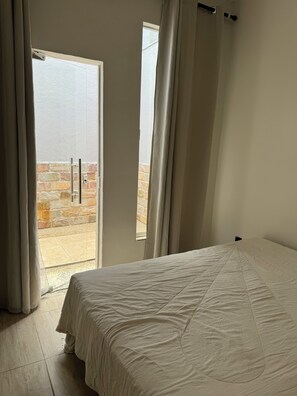 Relax in this serene space with a large bed and a balcony offering a view of the surrounding area.
