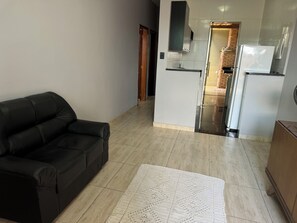 Cozy living space with a sofa and kitchen area, featuring a modern design and a woven rug.