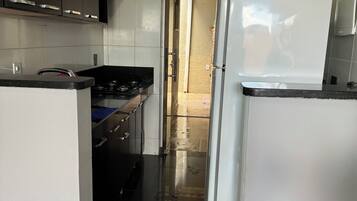Enjoy cooking in this well-equipped kitchen with a gas stove, refrigerator, and dark-colored cabinets.