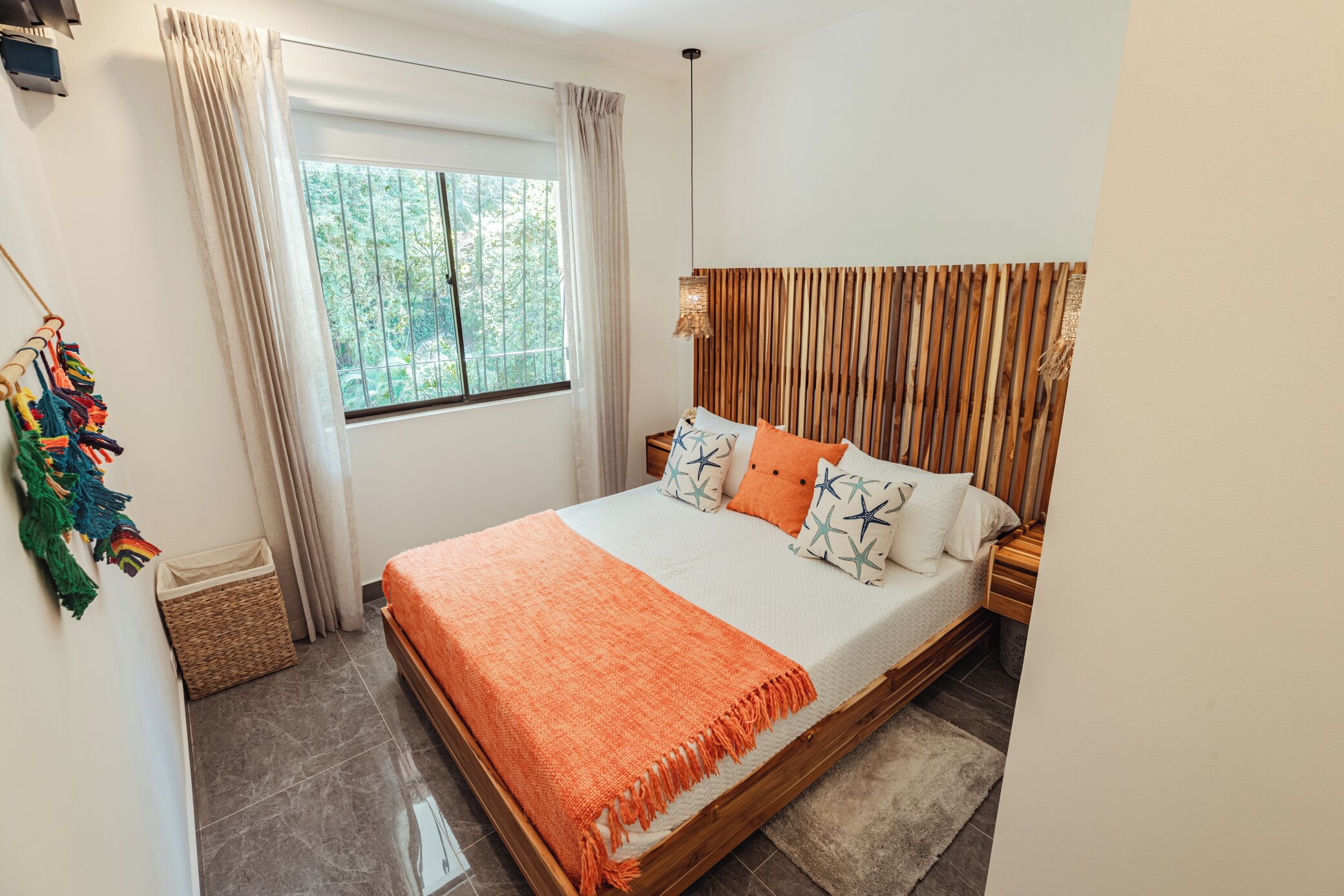 A bedroom with a bed, curtains, a window, and a wooden headboard.