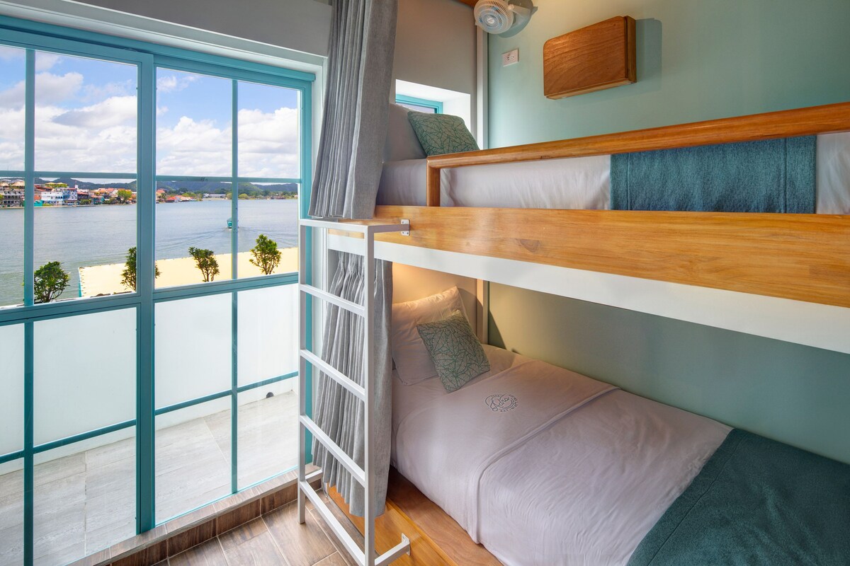 A bunk bed room with a view of a body of water and buildings in the distance.