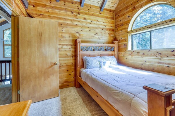 Un dormitorio de cabaña de madera con una cama, una ventana y una puerta.