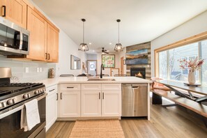 A modern kitchen with wooden cabinets, stainless steel appliances, a central island, and a large window providing a view of the outside. - Monthly Lease  - Porchlight Retreat by Tahoe Getaways, 3BR Dog Friendly in Truckee (Truckee)