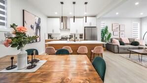 A modern kitchen with white cabinets, a central island, and pendant lighting. - ExoticLUSHquietRetreatKingBed|WIFI|Parking|WEM (Edmonton)