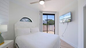 A bedroom with a bed, a ceiling fan, a TV, and a view of the outside. - Surfside G19 - Condo in Surfside Resort with Many Shared Amenities (Miramar Beach)