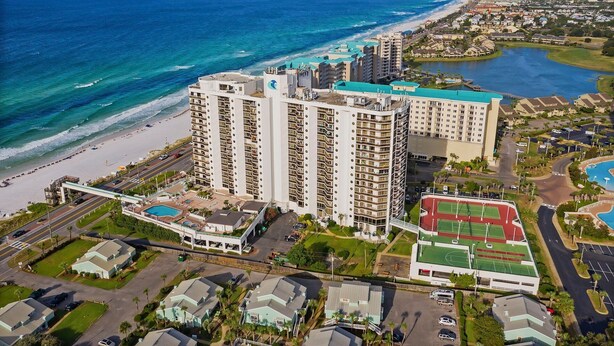 A high-rise hotel with multiple floors, a swimming pool, tennis courts, and a beach view. - Surfside G19 - Condo in Surfside Resort with Many Shared Amenities (Miramar Beach)