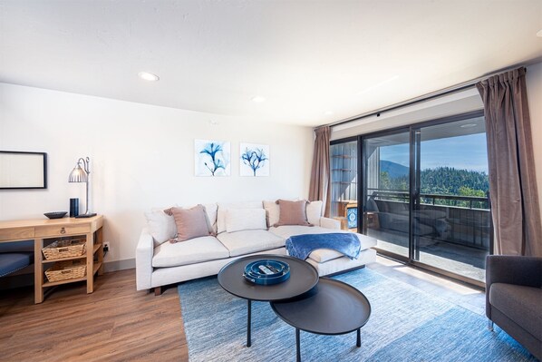 A modern living room with a sofa, a coffee table, and a view of a balcony.