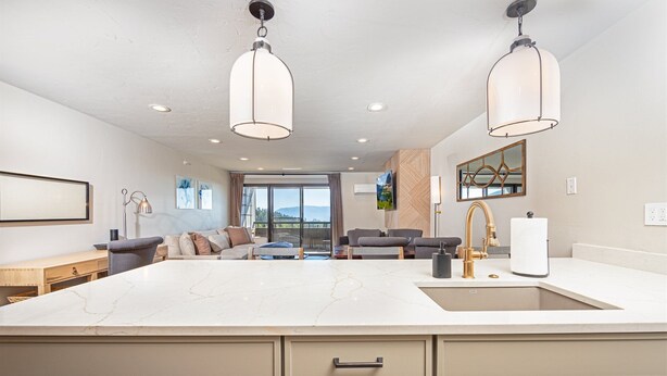 A spacious kitchen with a large island, modern pendant lights, and a view to the outdoors. - Newley renovated ski-in/ ski-out duel condo w communal hot tub and great views (Whitefish)