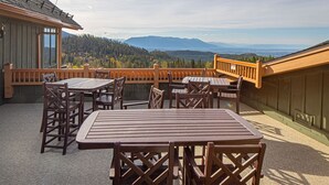 Una terraza de madera con mesa y sillas, con vistas a un paisaje montañoso.