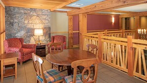 Un rincón comedor acogedor con pared de piedra, mobiliario de madera y chimenea.