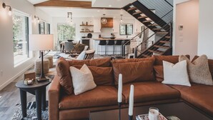 Ein modernes Wohnzimmer mit einer braunen Ledersofa, einem Couchtisch und einer Treppe, die in einen oberen Bereich führt.