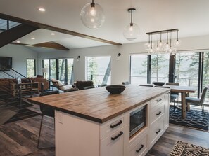 Una cocina moderna con una isla grande, iluminación colgante y ventanas amplias con vistas.
