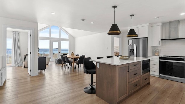 A modern kitchen with a large island, stainless steel appliances, and pendant lighting. - Foley’s Harbour House (Alberton)
