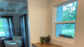Eine Küche mit Holzausziehtisch, drei Barhocker, einem Fenster mit Blick auf Grünflächen und einem gemusterten Teppich.