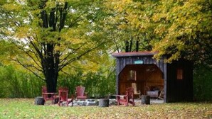 Ein rustikales Blockhaus mit Veranda, umgeben von Bäumen und Herbstlaub.