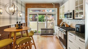 Une cuisine moderne avec un coin repas, comprenant une table en bois, des chaises et un lustre.