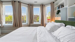 Une chambre d’hôtel avec un grand lit, un radiateur, une bibliothèque et une vue sur l’extérieur.