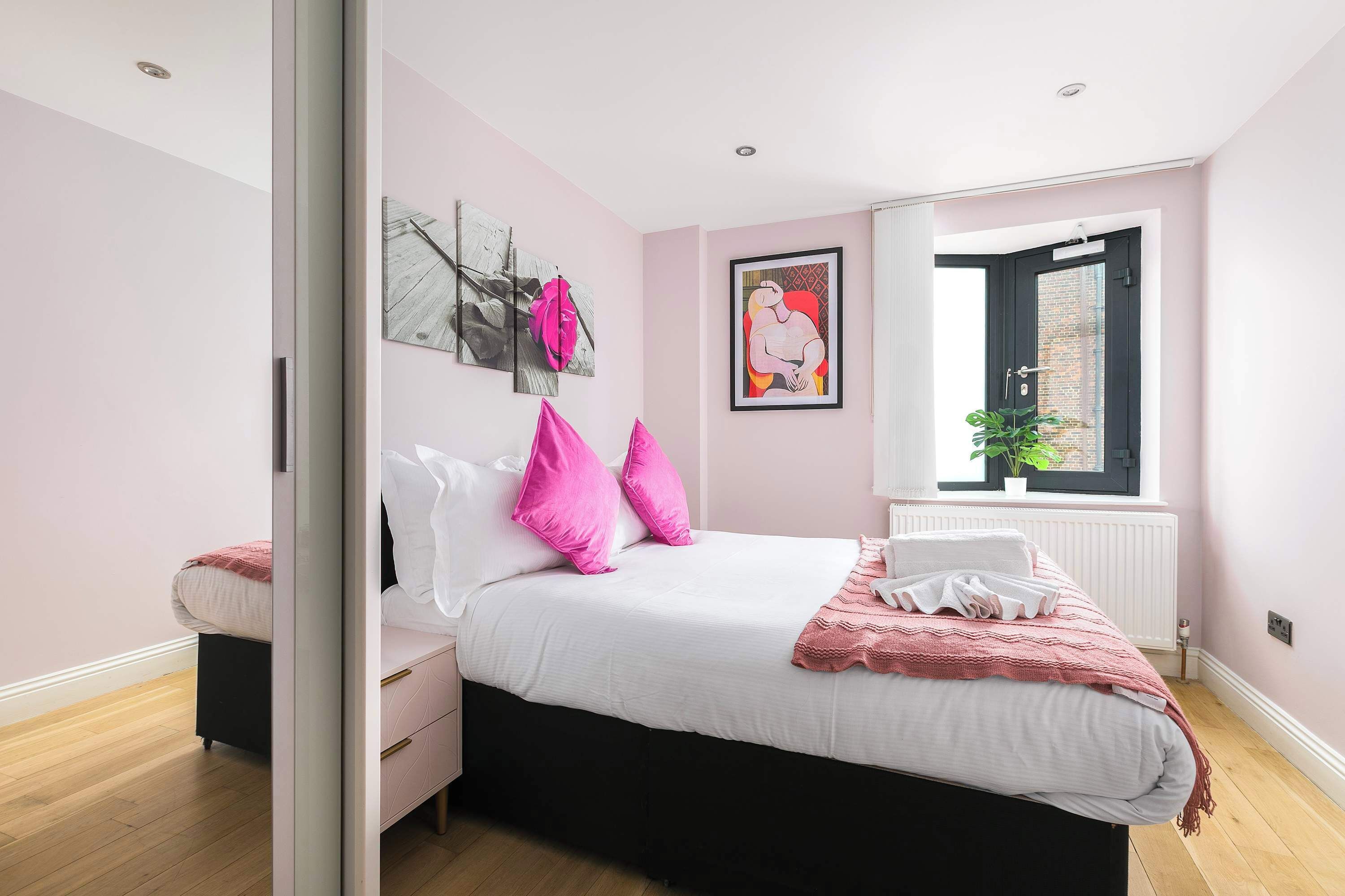 Ein Schlafzimmer mit Bett, Kommode, Fenster und Heizkörper.