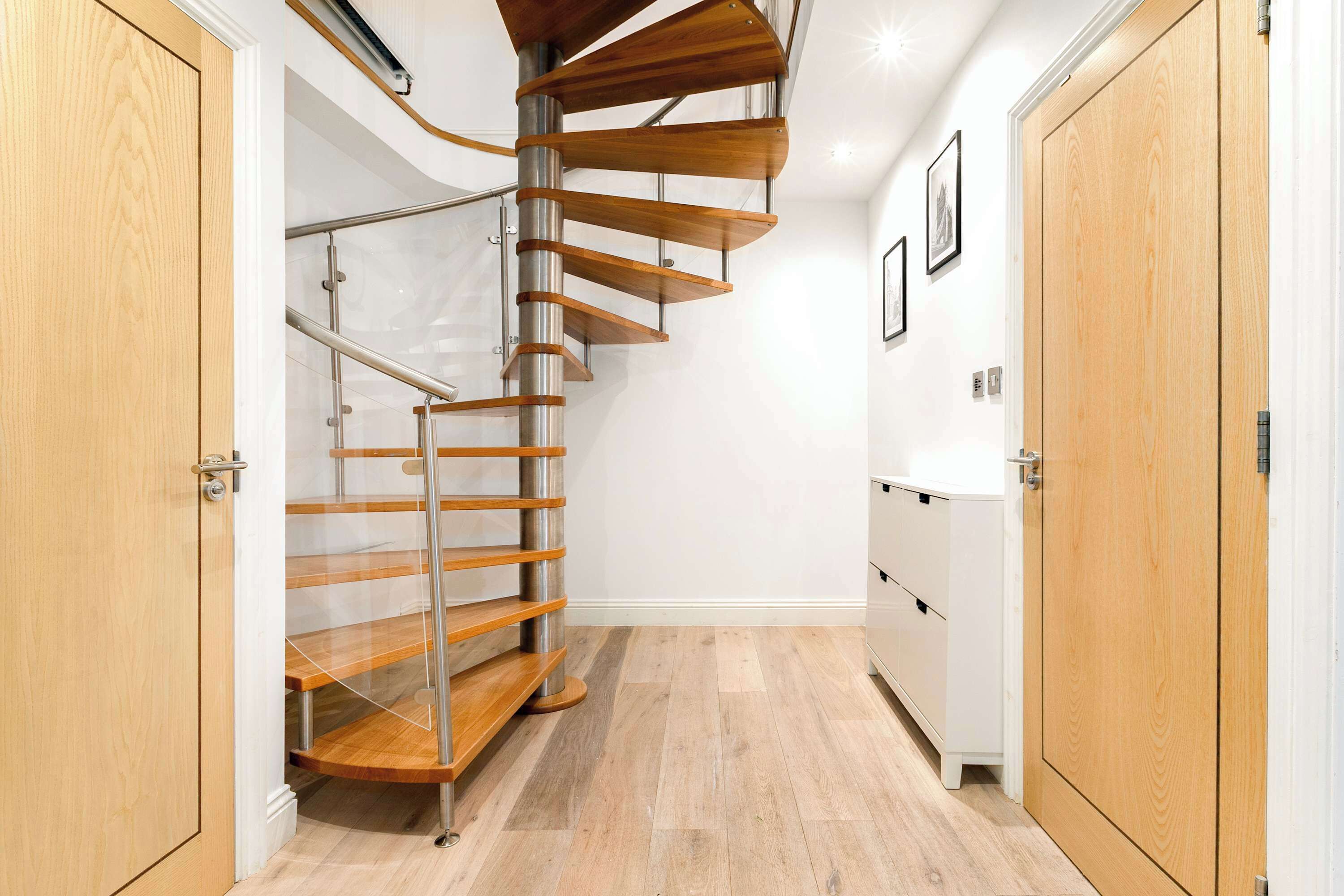 Un intérieur moderne avec un escalier en colimaçon, un plancher en bois et des murs blancs.