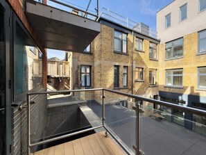 Ein modernes Gebäude mit einem Glasbalkon, Ziegelwänden und einem Metallgeländer.