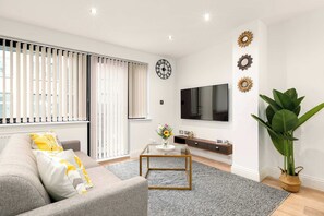 A modern living room with a sofa, coffee table, TV, and decorative wall pieces. - Angel 2 BR, 2 Bath Duplex with Balcony Sleeps 5 (Greater London)