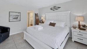A neatly arranged bedroom with a large bed, a bedside table, a lamp, and a chair. - El Matador 339 -  FREE TICKETS!! Your stay includes free tickets to many area attractions! (Fort Walton Beach)