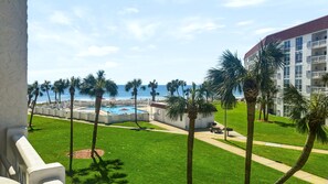 A resort with a swimming pool, palm trees, and a view of the ocean.