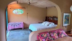 Una habitación acogedora con una cama, una cama individual, una estantería y una ventana con vistas.