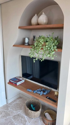 Relax in a clean and functional living space with a shelf, console table, and potted plant.