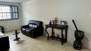 Uma sala de estar com um sofá de couro preto, uma mesa de centro de madeira, um globo e um pilão com almofariz.