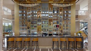 A bar area with multiple shelves of liquor bottles, a bar counter, and several bar stools. - Golden Tulip Kin-Oasis Kinshasa (Kinshasa)